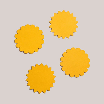 A set of yellow Sunburst Felt Cocktail Napkins spread out on a white seamless background.