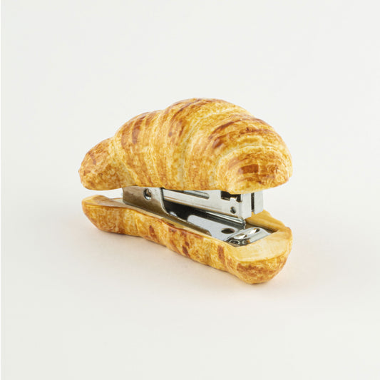 Hand-painted porcelain croissant stapler on a white seamless background.