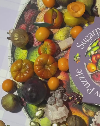Piecework Puzzles' 750-piece round jigsaw puzzles Sugarplum Cookie Tin featured in a video compiling the original puzzle art photoshoot of a tin on holiday marzipan and cookies, alongside moments from the product shoot showcasing the stripey collectible tin.